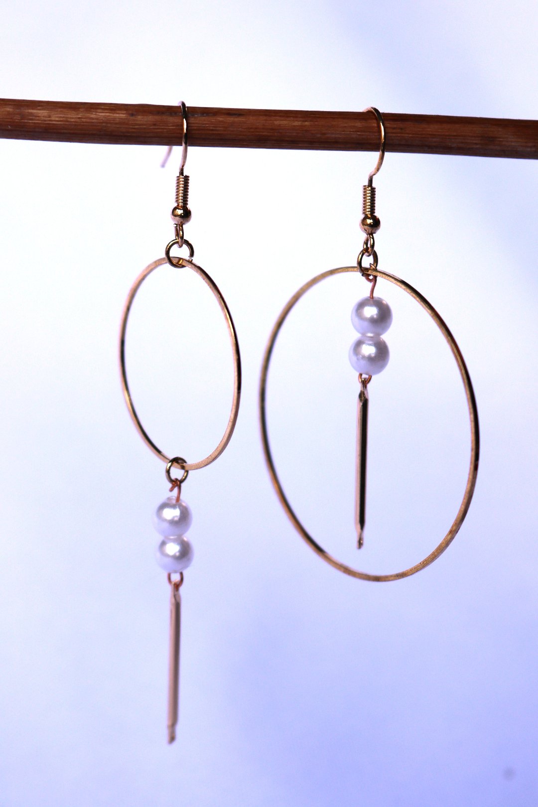 Boucles d'oreille faite à la main composées d'un anneau dorée et de deux perles blanches